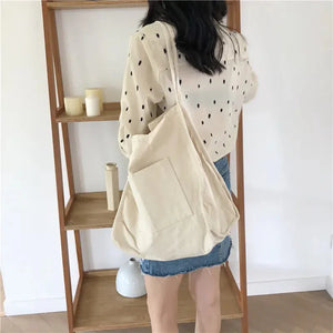 Woman wearing a polka dot blouse, denim skirt, and carrying a large beige canvas tote bag.
