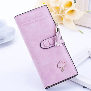 Pastel pink wallet with tassel charm and umbrella emblem, stylish accessory on white background