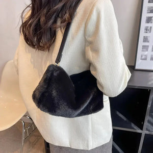 Woman in a cream blazer carrying a black faux fur shoulder bag indoors