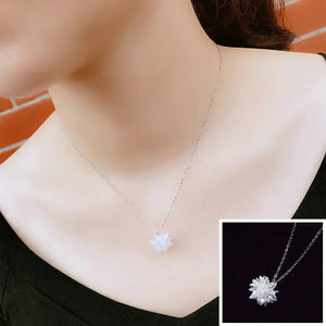 Woman wearing silver chain necklace with white crystal flower pendant, close-up view