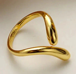 Modern open gold ring with abstract curved design on neutral background