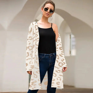 Woman wearing beige leopard print cardigan, black tank top, blue jeans, and sunglasses