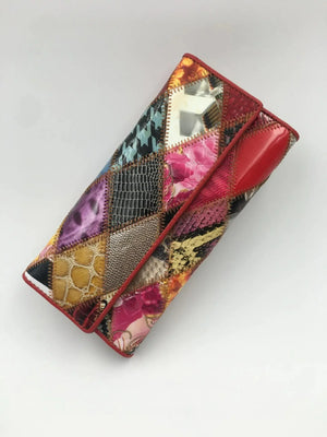 Colorful patchwork clutch wallet with mixed prints and textured leather, on white background
