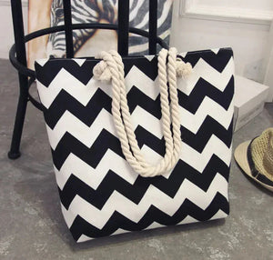 Black and white zigzag tote bag with thick rope handles on concrete floor
