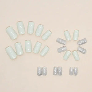 Set of press-on nails in glossy white and silver glitter styles on a neutral background