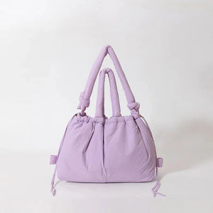 Soft pastel purple puffer handbag with knotted handles on white background