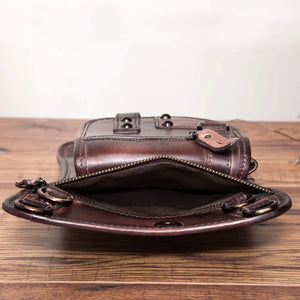 Open brown leather crossbody bag with zipper pocket on wooden table