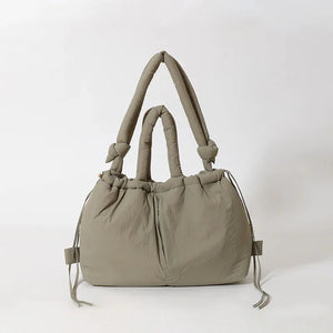 Beige padded handbag with knotted handles and drawstring details on a white background