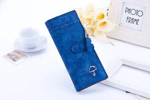 Blue women's wallet with tassel and umbrella charm, floral and decor background