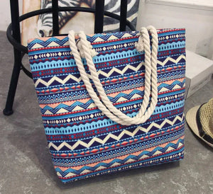Colorful patterned tote bag with white rope handles on a gray floor