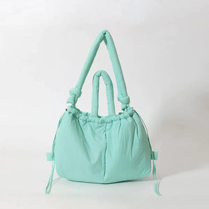 Mint green puffy handbag with padded handles and drawstring details on white background