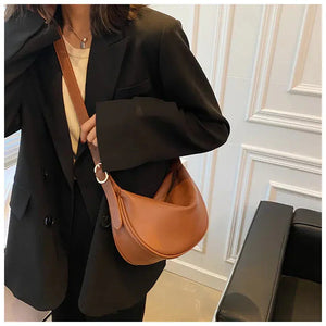 Woman wearing a black blazer with a stylish brown leather crossbody bag indoors