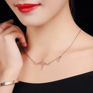 Woman wearing a heartbeat heart pendant necklace, delicate rose gold jewelry