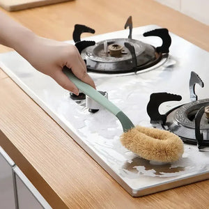 Hand cleaning stovetop with scrub brush, kitchen cleaning tool in use