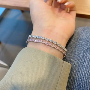Woman wearing two tennis bracelets with clear and pink gemstones, elegant fashion jewelry