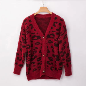 Red fuzzy cardigan with black leopard print and button closure, hanging on wooden hanger
