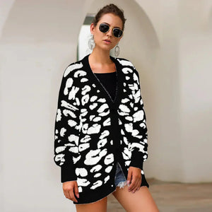 Woman in black and white animal print cardigan, black top, and sunglasses standing indoors