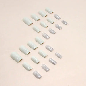 Set of white and glitter press-on nails arranged on a light beige background