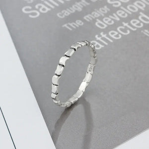 Textured sterling silver ring with geometric pattern on a gray background